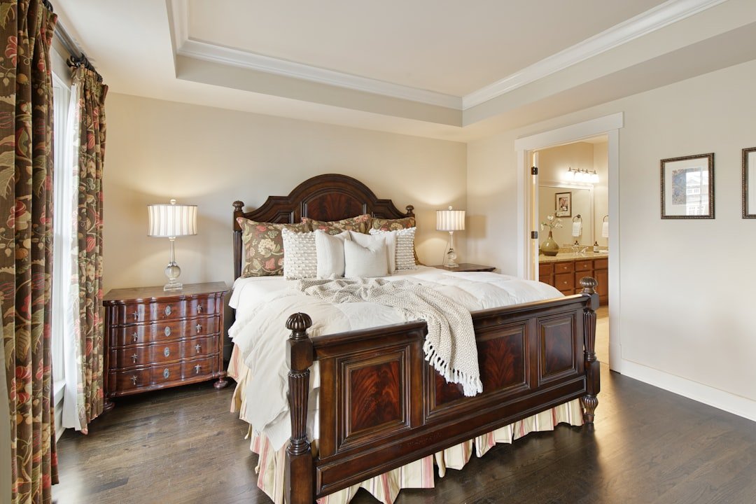 Well-crafted cherry-toned wooden bed and dresser in a warm bedroom, illustrating durable bedroom furniture