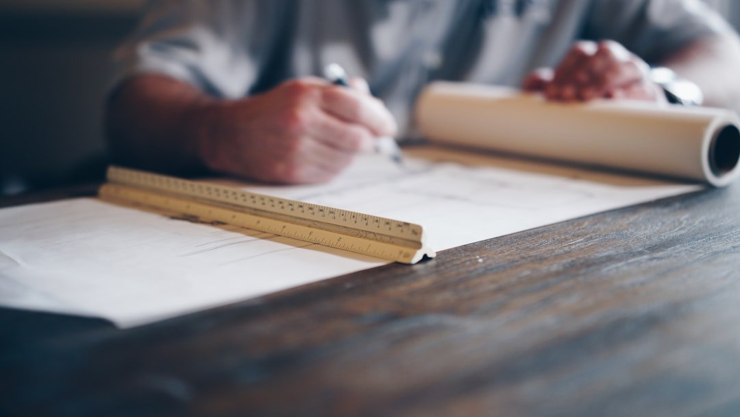 Renovation planning and budgeting — photo by Daniel McCullough on Unsplash Designer reviewing renovation plans and measurements at a desk while preparing a project budget