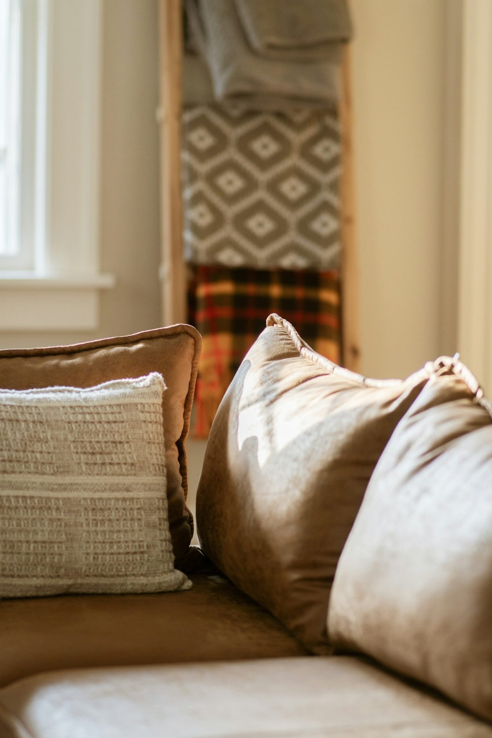 Cozy living room layered with soft blankets, pillows and warm brown and neutral textiles