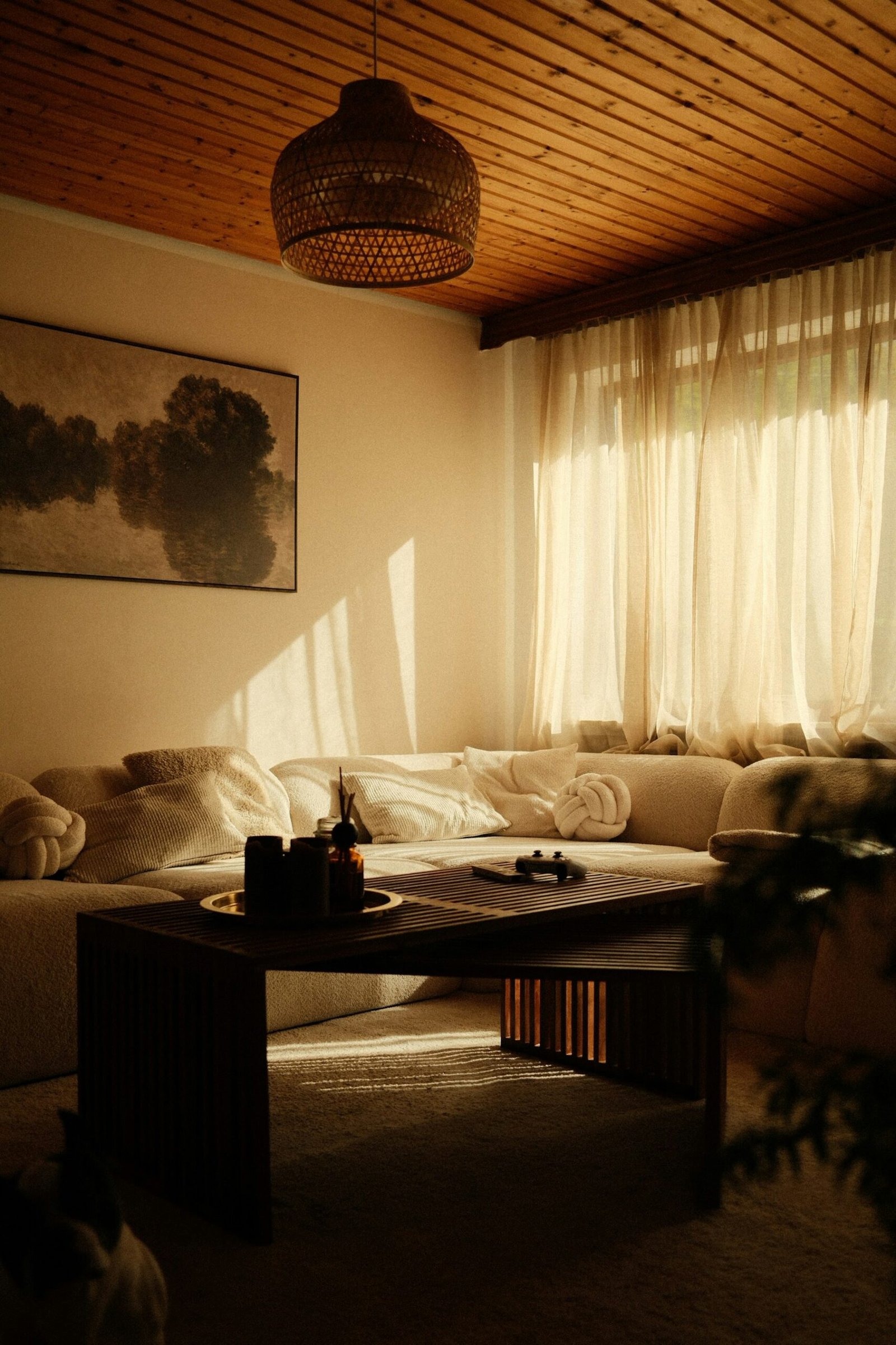 Warm living room with teak wood furniture, soft neutral upholstery and filtered natural light