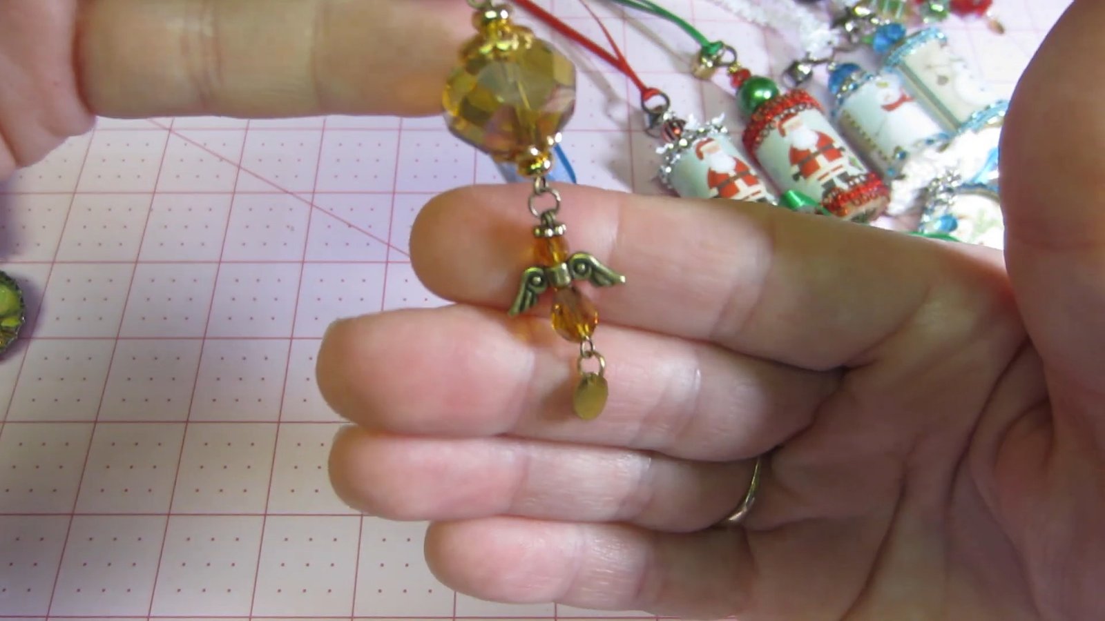 Amber-colored bead and small angel charm hanging below a gold ornament