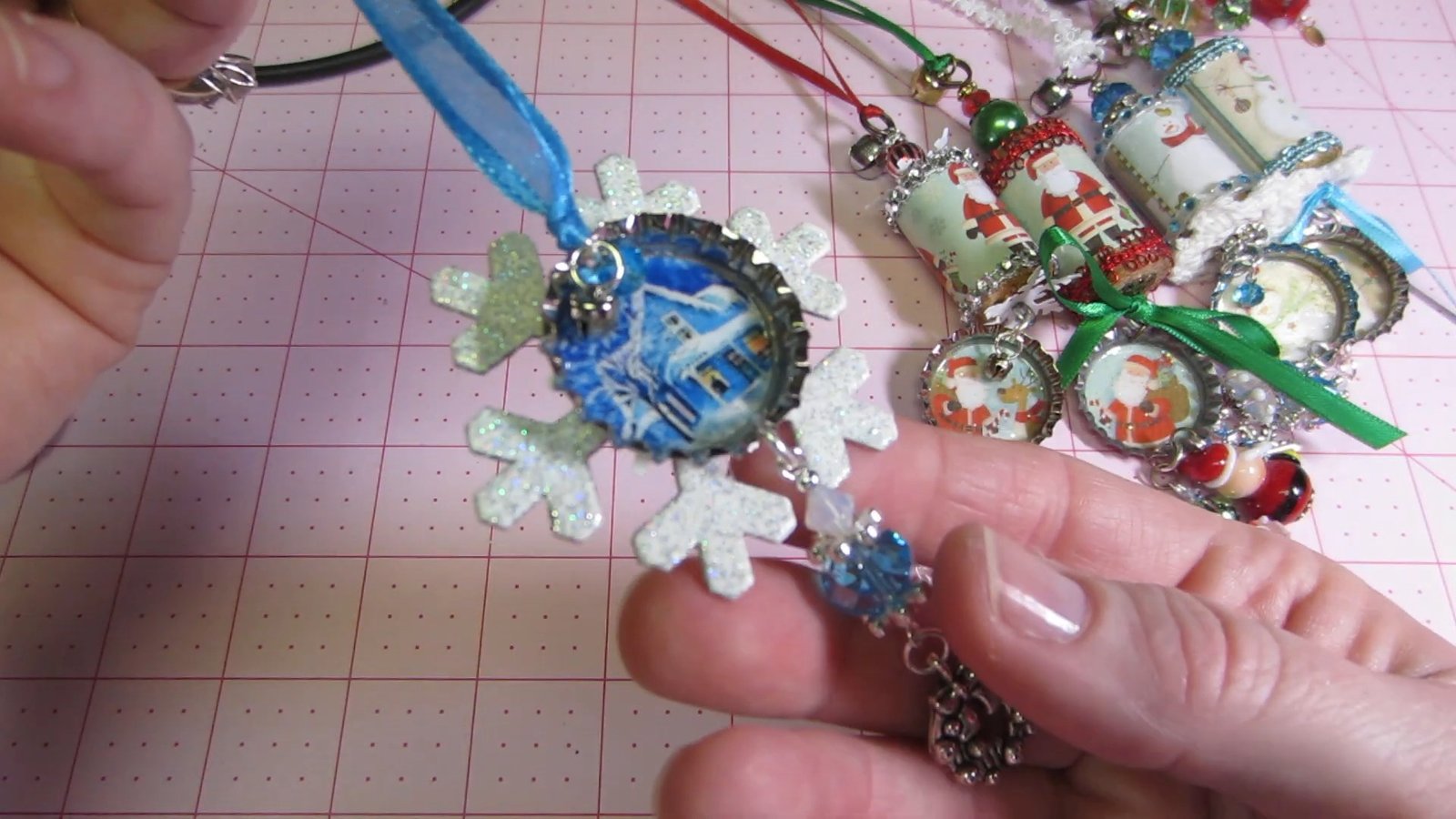 Blue bottle-cap medallion layered over a white snowflake with a beaded hanging charm