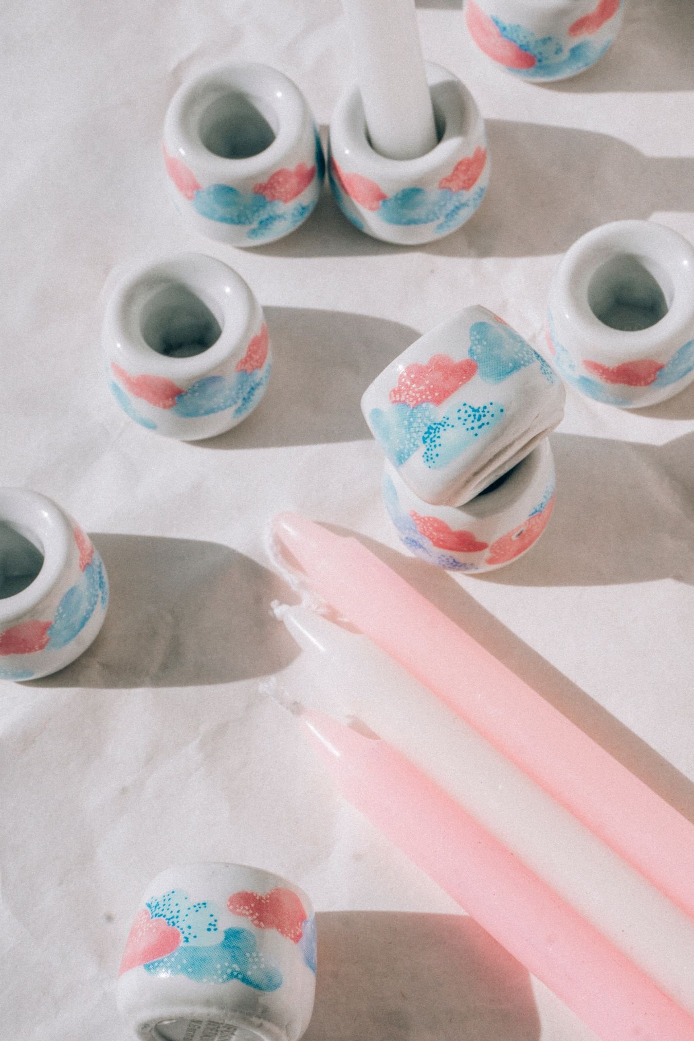 Colorful handmade ceramic candle holders with pink taper candles in a studio still life