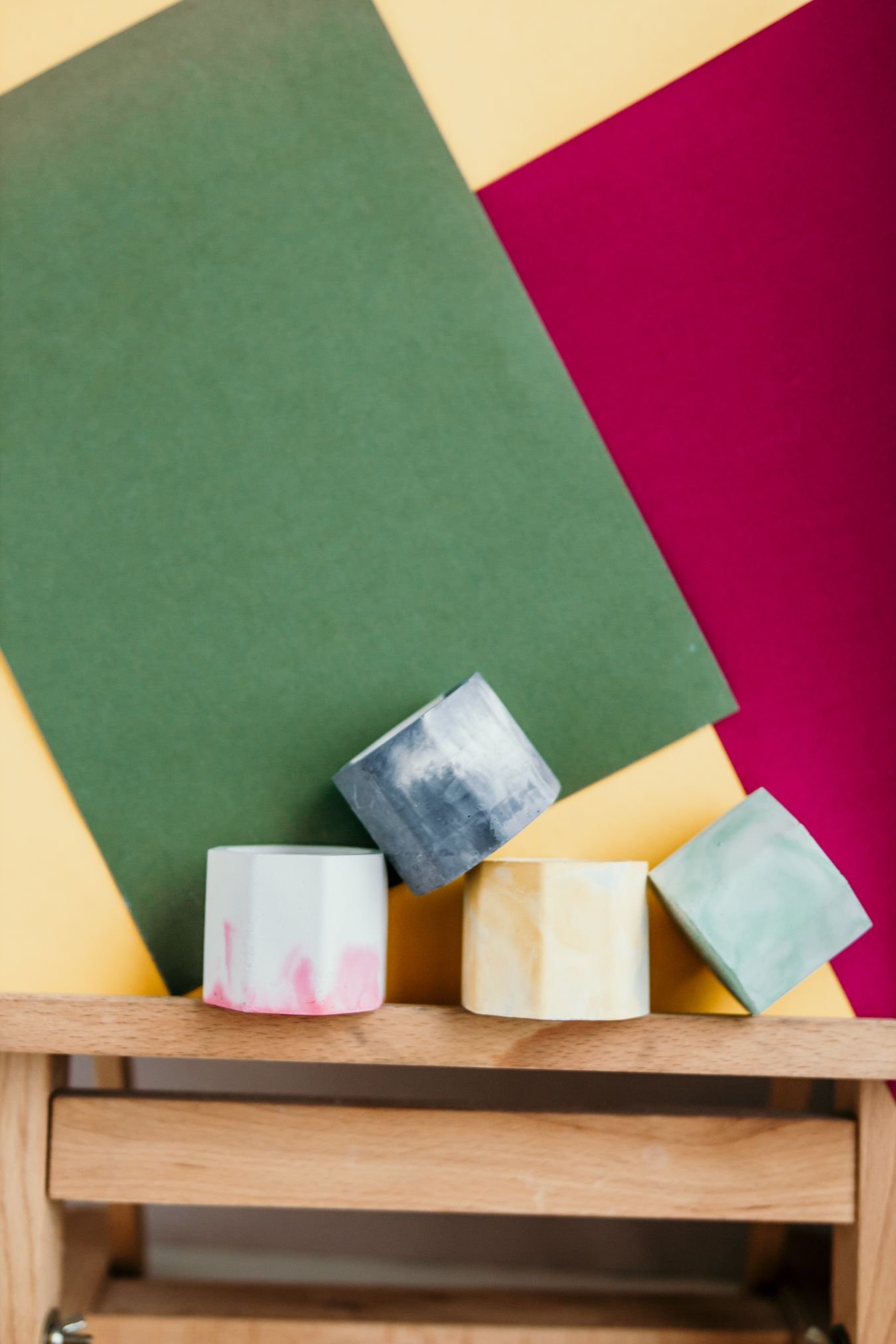 Handmade colorful geometric candle holders displayed against bold colored paper