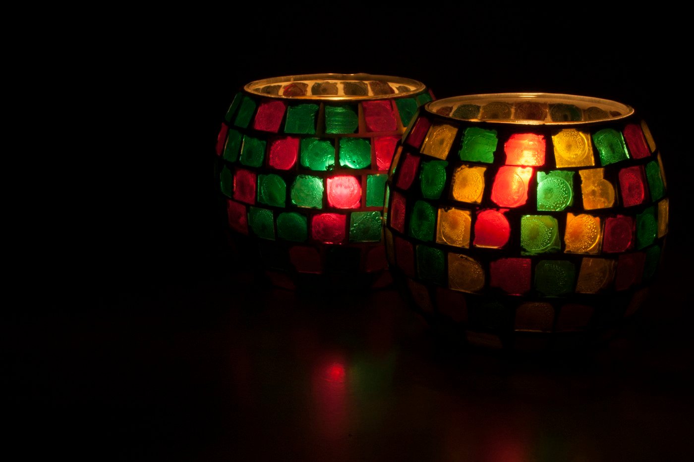 Red, green and yellow mosaic candle holders glowing with colored light