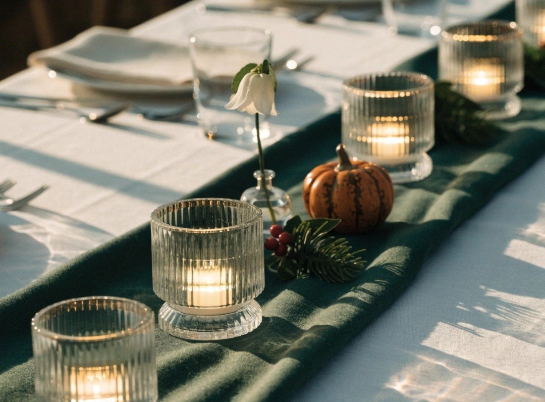 Three seasonal dining table centerpiece arrangements using the same LED votives and linen runner with spring flowers, fall ceramic pumpkins and winter greenery.